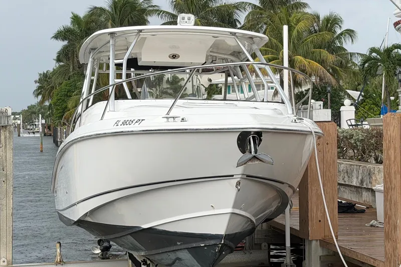 Slide: The Image of 2007 Boston Whaler 320 Outrage boat docked near waterfront homes and palm trees. - 2