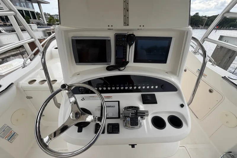 Slide: The Image of 2007 Boston Whaler 320 Outrage helm with dual displays and steering wheel, docked by the water. - 27