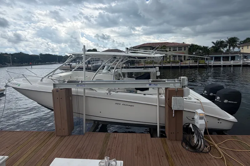 Slide: The Image of 2007 Boston Whaler 320 Outrage docked by waterfront homes under cloudy skies. - 4