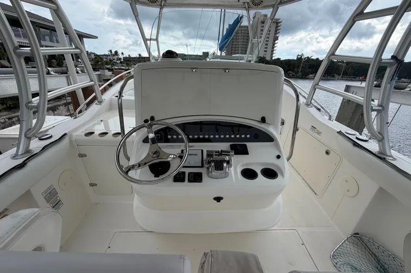 Slide: The Image of 2007 Boston Whaler 320 Outrage helm with steering wheel and control panel, docked by water. - 22