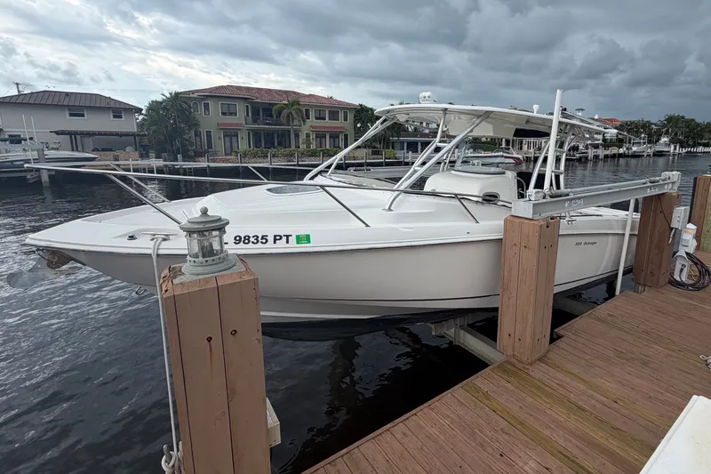 Slide: The Image of 2007 Boston Whaler 320 Outrage docked by waterfront homes under cloudy skies. - 6