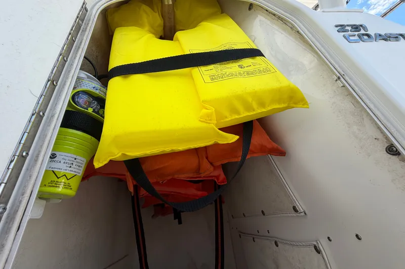 Slide: The Image of Un compartiment de rangement avec des gilets de sauvetage jaunes et orange et une fusée de détresse. - 37