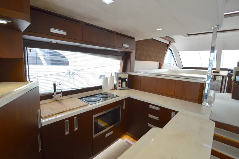 Slide: The Image of The 2016 Galeon 550 Fly features a modern kitchen with wooden cabinets and white countertops. - 26