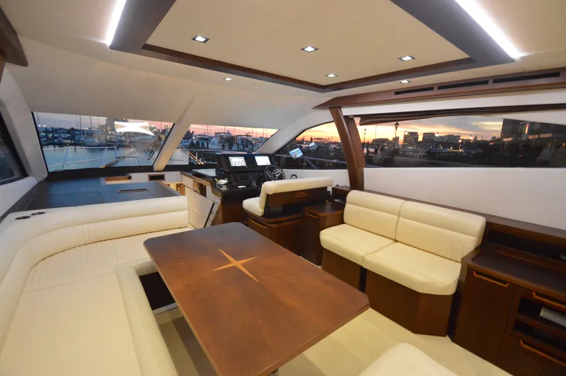 Slide: The Image of Interior of a 2016 Galeon 550 Fly with elegant white seating and a wooden table. - 30