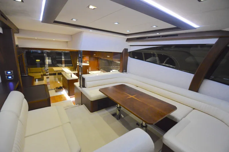 Slide: The Image of Interior of the 2016 Galeon 550 Fly with elegant white seating and a wooden table. - 29
