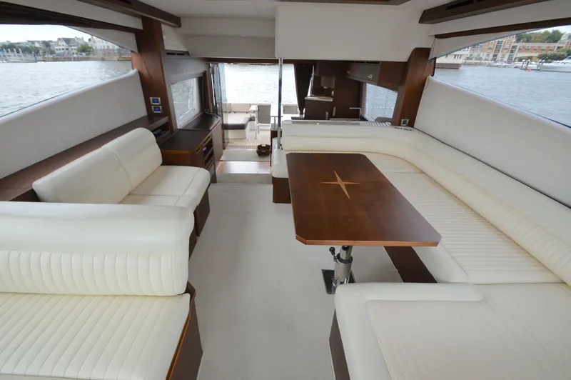 Slide: The Image of Interior of the 2016 Galeon 550 Fly with elegant white seating and a wooden table. - 35