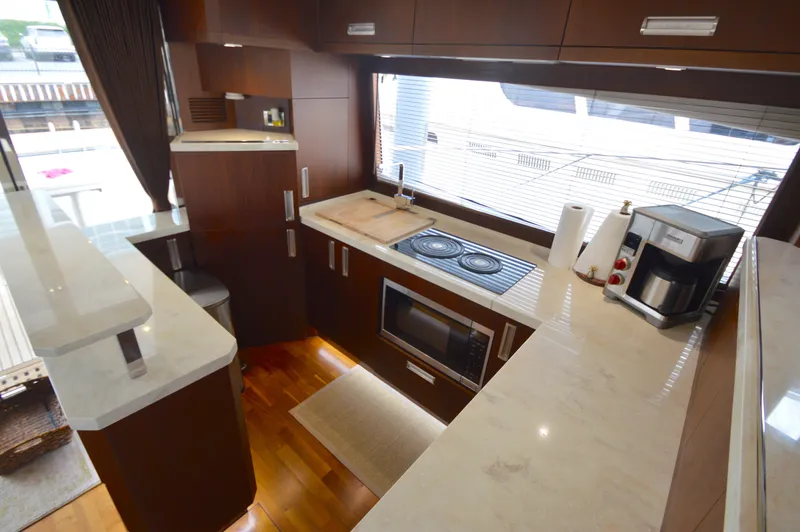 Slide: The Image of The 2016 Galeon 550 Fly features a modern kitchen with wood cabinets and marble countertops. - 25