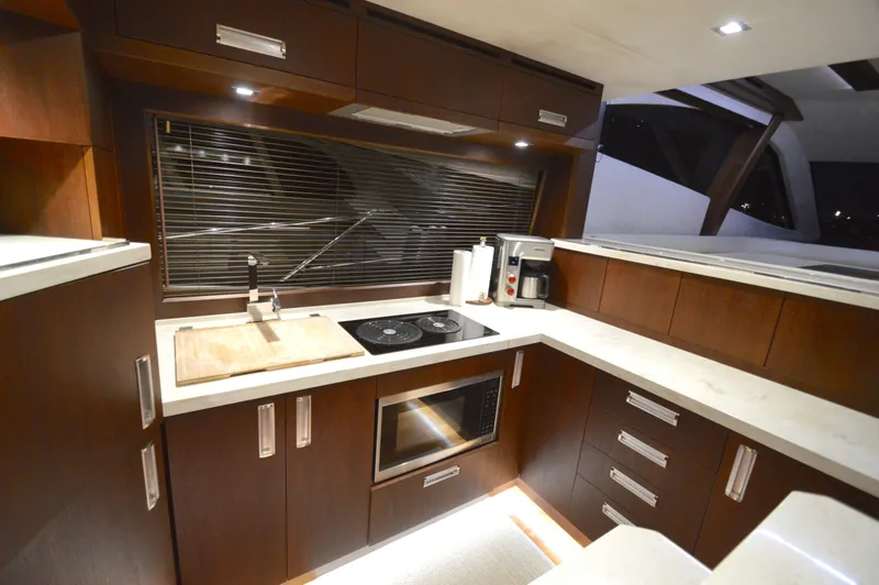 Slide: The Image of The 2016 Galeon 550 Fly features a modern kitchen with wooden cabinets, stove, and microwave. - 23
