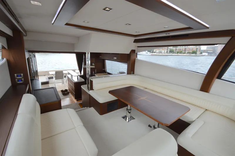 Slide: The Image of Interior of a 2016 Galeon 550 Fly with elegant white seating and a wooden table. - 32