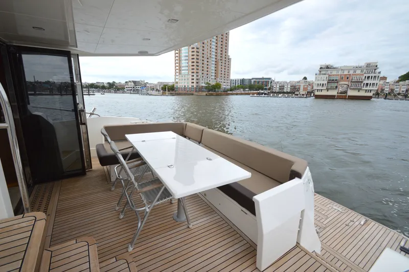 Slide: The Image of The 2016 Galeon 550 Fly features an elegant deck with a table and seating by the water. - 16