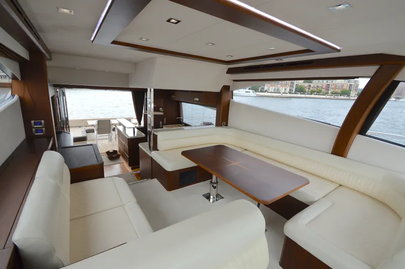 Slide: The Image of Interior of a 2016 Galeon 550 Fly with elegant white seating and a wooden table. - 34