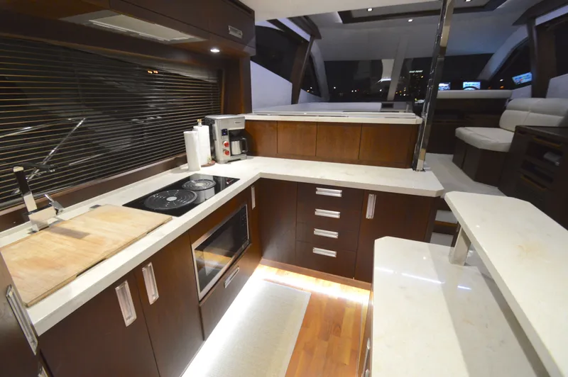 Slide: The Image of The 2016 Galeon 550 Fly features a modern kitchen with wooden cabinets and white countertops. - 22
