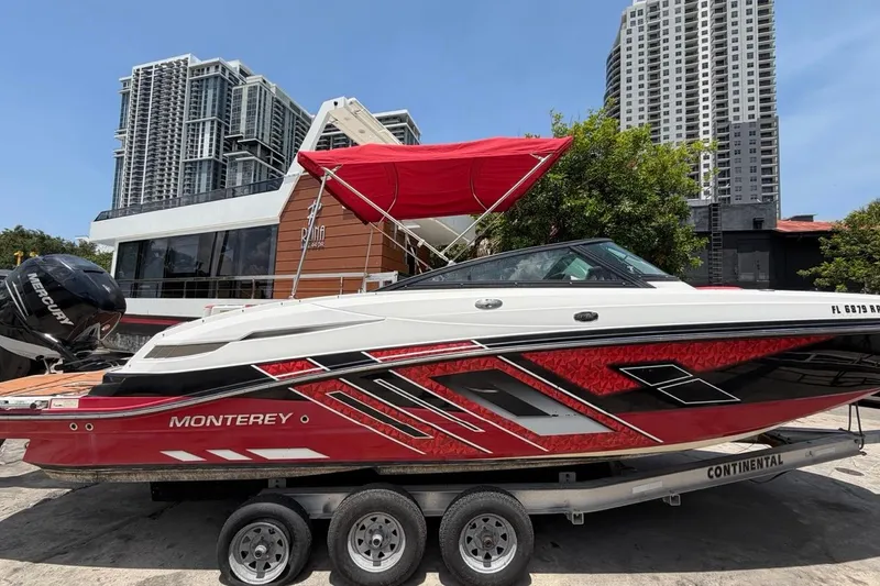 Slide: The Image of 2017 Monterey M-65 boat with red accents on a trailer, urban skyline background. - 5