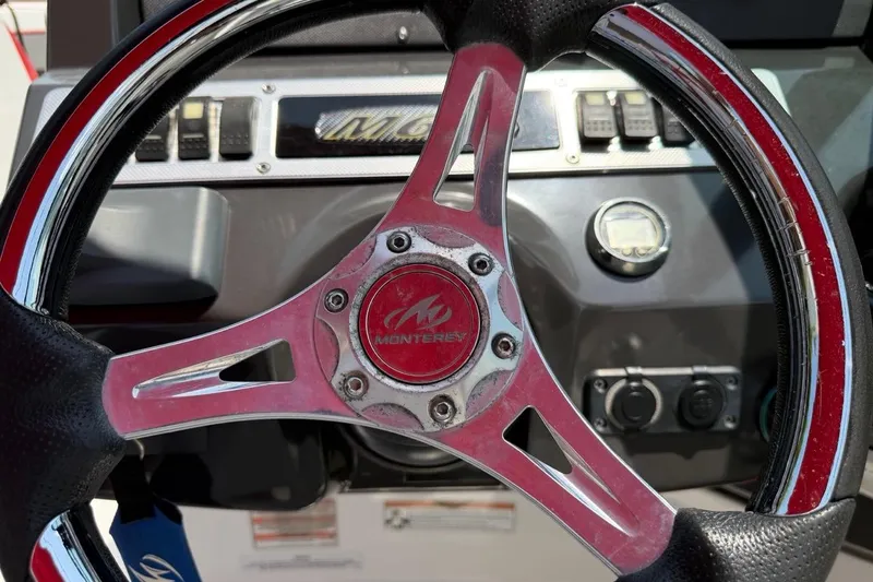 Slide: The Image of Steering wheel of a 2017 Monterey M-65 boat, featuring a sleek design and control panel. - 115