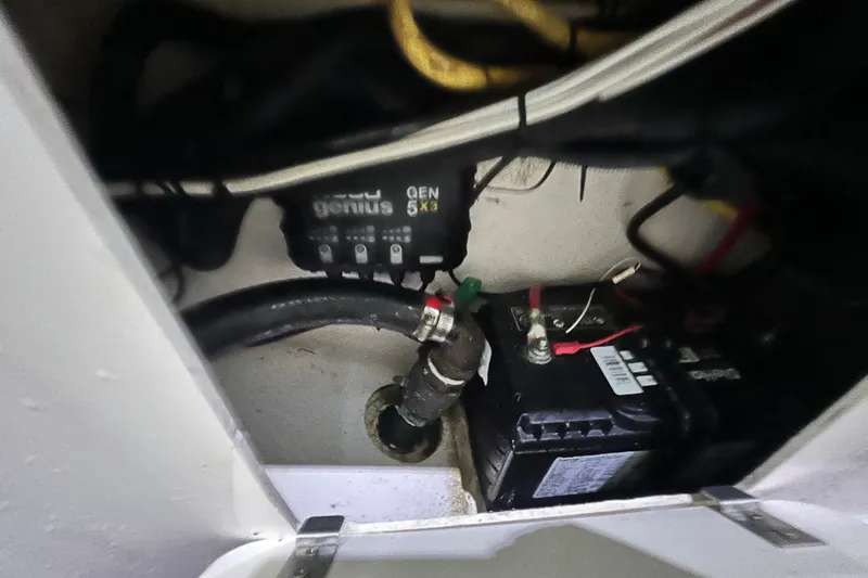 Slide: The Image of 2017 Pursuit C 238 Center Console battery compartment with wiring and charger. - 94