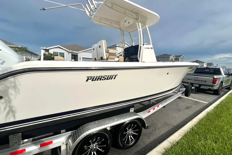 Slide: The Image of 2017 Pursuit C 238 Center Console boat on trailer, parked beside a truck. - 3