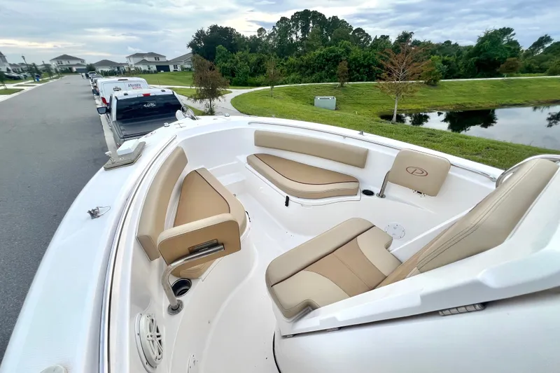 Slide: The Image of 2017 Pursuit C 238 Center Console boat with tan seating, parked near a residential area. - 59