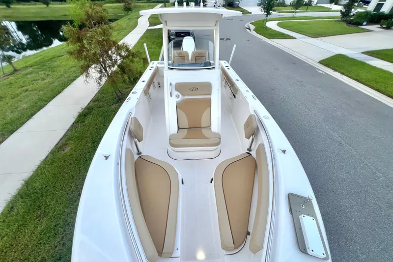 Slide: The Image of 2017 Pursuit C 238 Center Console boat with tan seating, parked on a residential street. - 77