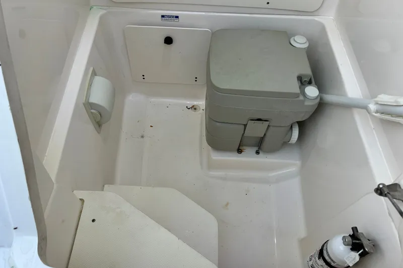 Slide: The Image of 2017 Pursuit C 238 Center Console boat interior with portable toilet and fire extinguisher. - 82