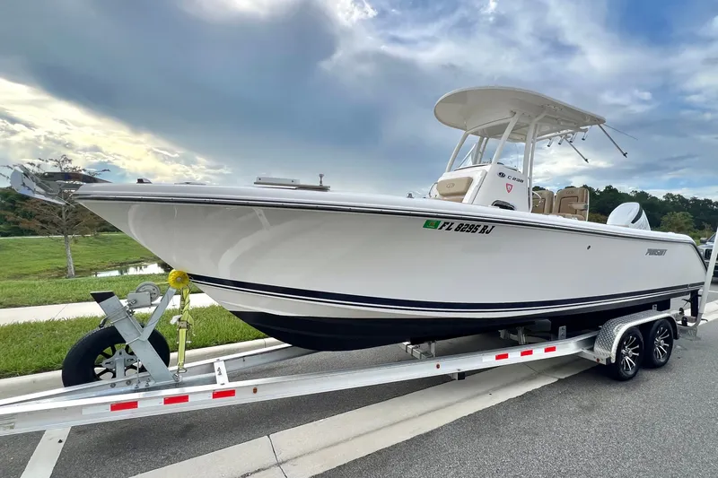 Slide: The Image of 2017 Pursuit C 238 Center Console boat on trailer, parked roadside under cloudy sky. - 16