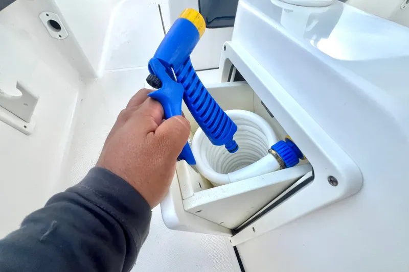Slide: The Image of Hand holding blue hose nozzle on 2017 Pursuit C 238 Center Console boat. - 72