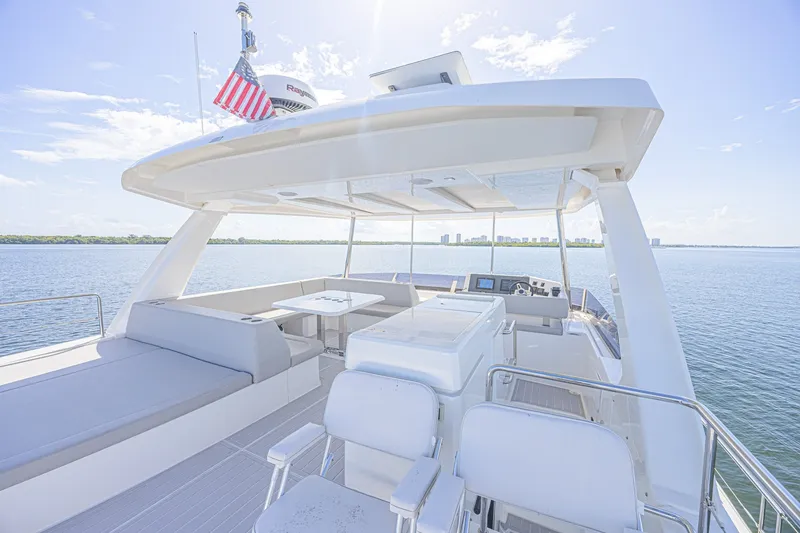 Slide: The Image of 2025 Leopard 53 Powercat yacht deck with seating, table, and helm, overlooking serene waters. - 20