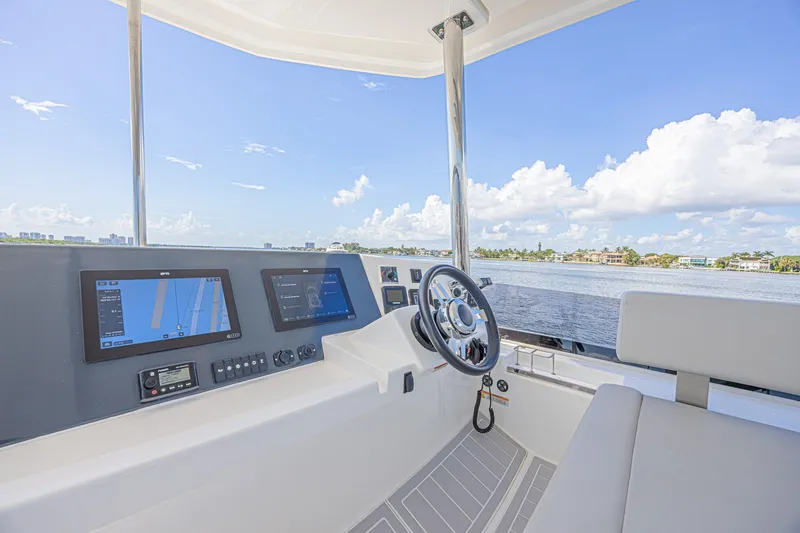 Slide: The Image of Helm of 2025 Leopard 53 Powercat with navigation screens and steering wheel, overlooking serene waters. - 29
