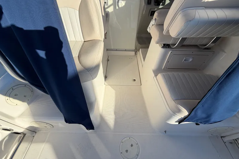 Slide: The Image of 2017 Robalo R265 Walkaround interior with blue curtains and cushioned seating. - 19