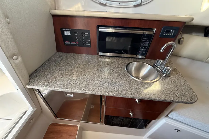 Slide: The Image of 2017 Robalo R265 Walkaround boat interior with kitchenette, featuring sink, microwave, and control panel. - 45