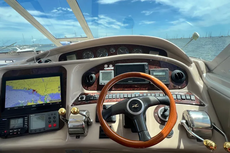 Slide: The Image of 2003 Sea Ray 480 Motor Yacht helm with navigation screens and wooden steering wheel. - 88