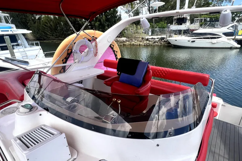 Slide: The Image of 2002 Sea Ray 450 Express Bridge with red seating and helm, docked near other boats. - 43