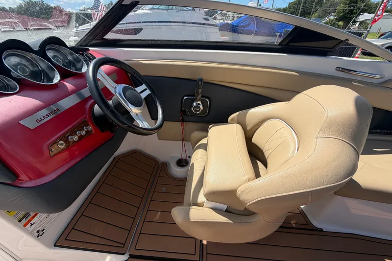 Slide: The Image of Interior of a 2016 Glastron GT 245 boat with beige seating and red dashboard. - 22