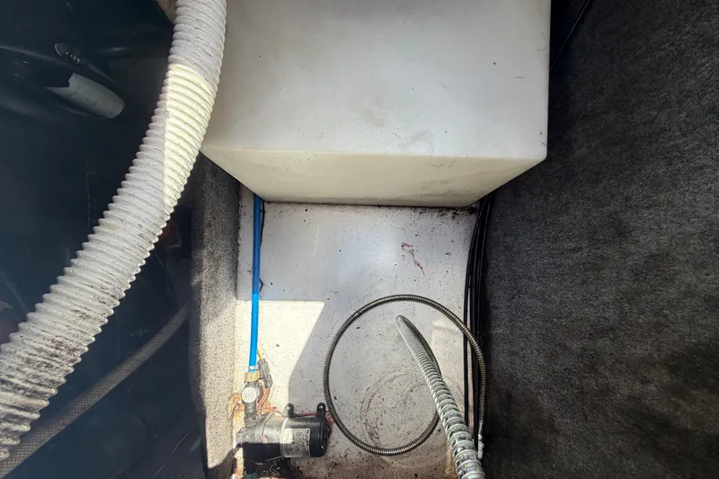 Slide: The Image of A boat engine compartment with hoses and a white tank. - 18