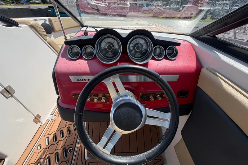 Slide: The Image of Steering wheel and dashboard of a 2016 Glastron GT 245 boat, featuring gauges and controls. - 24