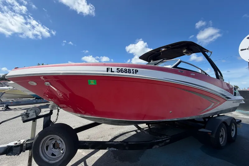 Slide: The Image of 2016 Glastron GT 245 boat in vibrant red on trailer under blue sky. - 8