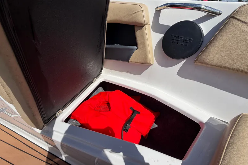 Slide: The Image of Storage compartment in 2016 Glastron GT 245 boat with red life jacket inside. - 51
