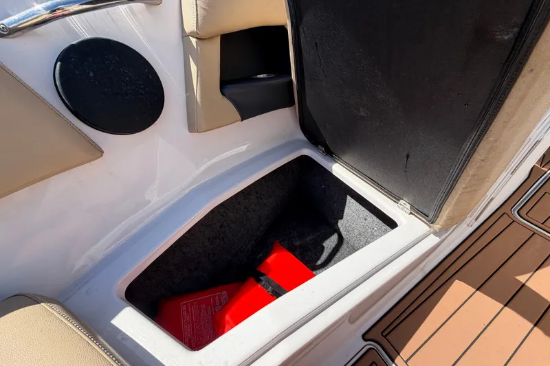 Slide: The Image of Storage compartment in a 2016 Glastron GT 245 boat, featuring a red safety kit. - 55