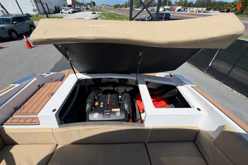Slide: The Image of 2016 Glastron GT 245 boat engine compartment with open hatch, revealing storage and engine. - 72