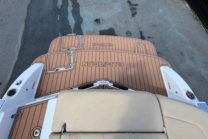 Slide: The Image of 2016 Glastron GT 245 boat deck with teak-style flooring and beige seating. - 77