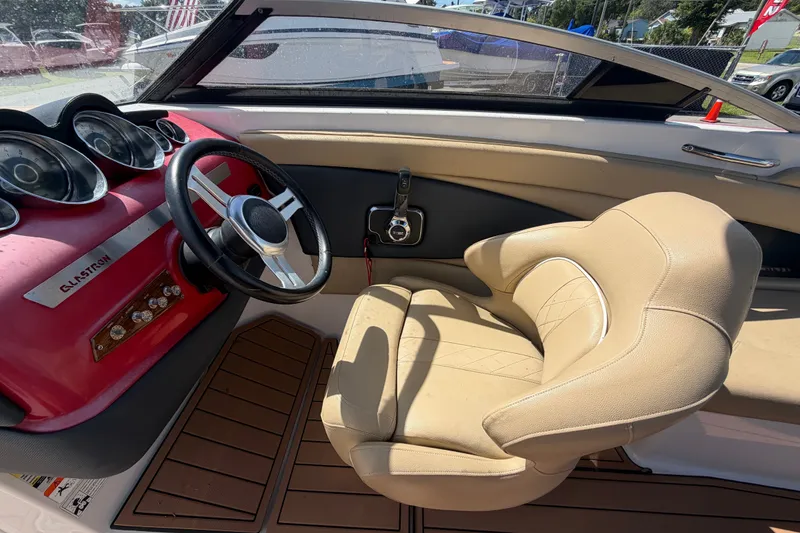 Slide: The Image of Interior of a 2016 Glastron GT 245 boat with beige seating and red dashboard. - 23