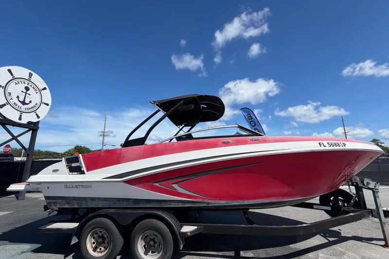Slide: The Image of 2016 Glastron GT 245 boat on trailer under clear blue sky. - 1