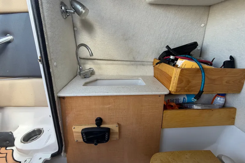 Slide: The Image of 2016 Glastron GT 245 boat interior with sink and storage shelves. - 34