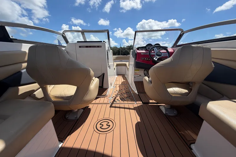 Slide: The Image of 2016 Glastron GT 245 boat interior with tan seats and wooden flooring under a blue sky. - 20