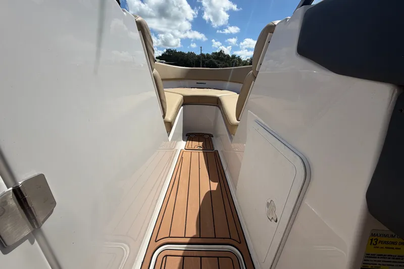 Slide: The Image of 2016 Glastron GT 245 boat interior with teak flooring and beige seating under blue sky. - 38
