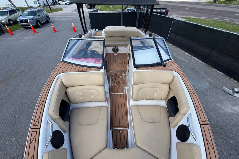 Slide: The Image of 2016 Glastron GT 245 boat with beige seating and wood-style deck, parked outdoors. - 49