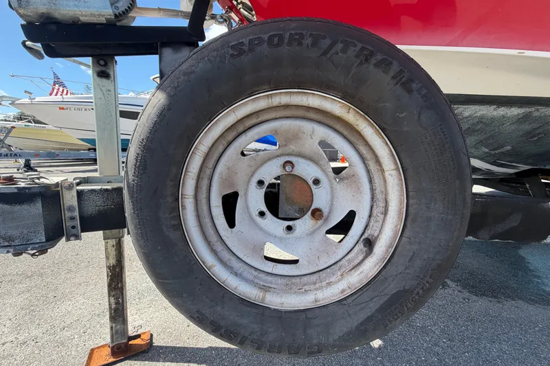 Slide: The Image of Trailer wheel of a 2016 Glastron GT 245 boat, parked on asphalt. - 84