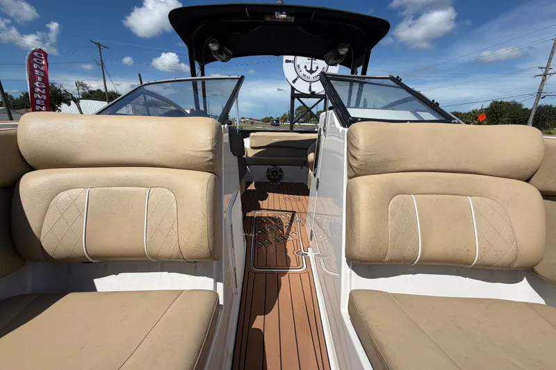 Slide: The Image of 2016 Glastron GT 245 boat interior with beige seating and wooden flooring under a clear sky. - 56