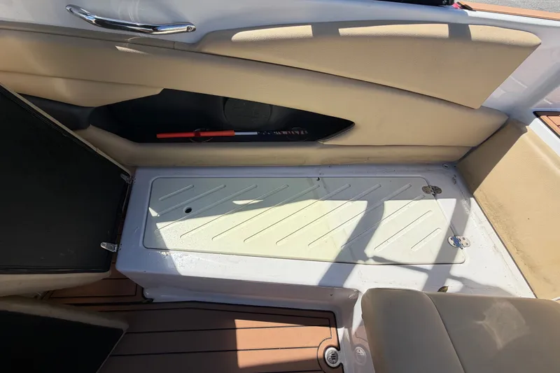 Slide: The Image of Interior of a 2016 Glastron GT 245 boat, featuring beige seating and storage compartment. - 64