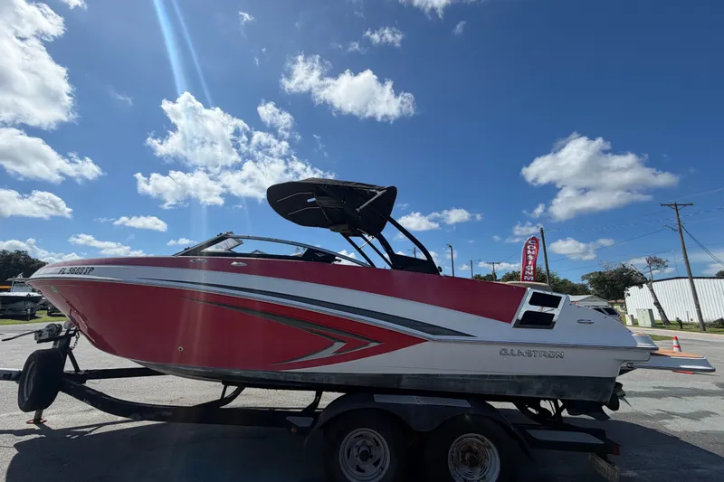 Slide: The Image of 2016 Glastron GT 245 boat on trailer under a clear blue sky. - 7
