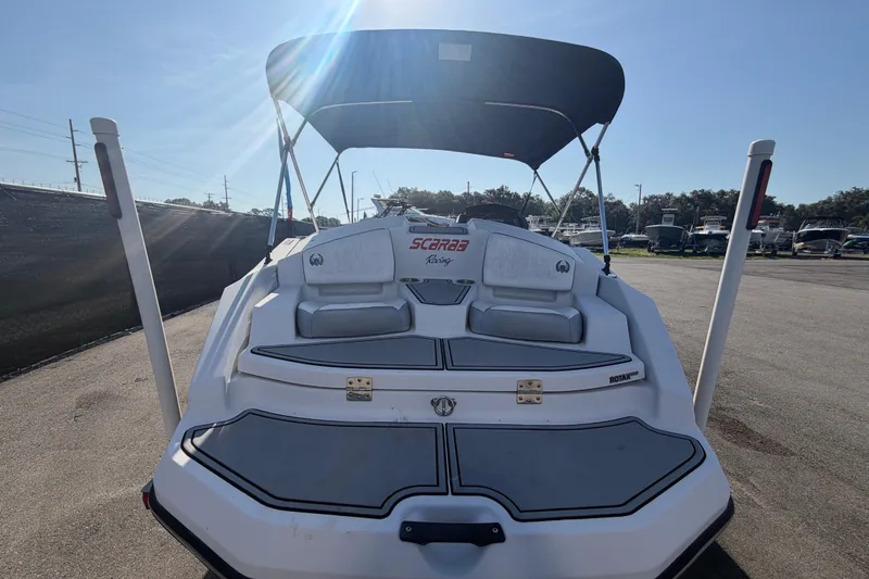 Slide: The Image of 2016 Scarab 165 boat with canopy, parked outdoors under clear blue sky. - 3